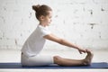 Girl child in paschimottanasana pose, white studio background