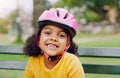 Girl child, portrait and helmet while happy outdoor on a park bench with a smile for safety gear. Face of black kid in Royalty Free Stock Photo