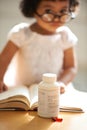 Girl, child and reading or book pill bottle or adhd diagnosis, learning or development. Kid, glasses and childhood Royalty Free Stock Photo