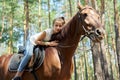 Girl child riding horse, summer horse ride in the forest, girl lovingly hugged horse