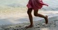 A Girl child runs along the river bank splashing water with his feet. In summer, the child plays on the beach, runs barefoot on Royalty Free Stock Photo