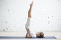 Girl child in Salamba Sarvangasana pose, white studio background