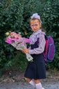 A girl child in school uniform with bows, glasses and a school bag on his back goes to the first class of the school on September Royalty Free Stock Photo