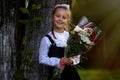 A girl child in school uniform goes to the school on September 1st. The girl is holding a bouquet of flowers. Close-up Royalty Free Stock Photo