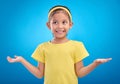 Girl, child and shrug with happy or unsure face in studio with arms and hands stretched with a smile. Kid on blue