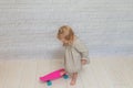 Girl, child on a skateboard on a white brick wall background