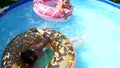 Girl child swim in donut pool float in outdoor swimming pool on sunny summer day, floatation