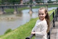 Girl child tourist enjoy sightseeing while walks. Kid girl with long hair walks near riverside, river on background Royalty Free Stock Photo