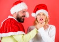 Girl choking while man hold her neck celebrate christmas. Man with beard and woman in santa hat on red background Royalty Free Stock Photo