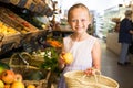 girl choosing apples in vegetable shop. on the signboard inscriptions in Catalan