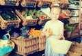 Girl choosing carrots in vegetable shop. on the signboard inscr