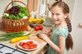 Girl chopping cucumber in kitchen, vegetables and fresh fruits in basket, healthy nutrition concept Royalty Free Stock Photo