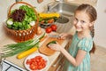 Girl chopping cucumber in kitchen, vegetables and fresh fruits in basket, healthy nutrition concept Royalty Free Stock Photo