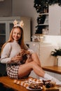 A girl on Christmas day sits on the kitchen table and holds a glass of champagne in her hands.A woman on New year`s eve in the Royalty Free Stock Photo