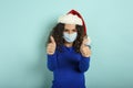 Girl with christmas hat is optimistic about the defeat of covid 19 coronavirus. cyan background.