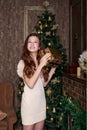 Cute girl with a christmas present in hands in delight happy standing in the living room of a classic style in a gold retro vintag