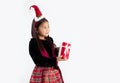 Girl in christmas theme costume wearing santa hat headband holding gift box and giving Royalty Free Stock Photo