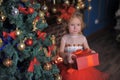 Girl at the Christmas tree in a red elegant dress with a box with gifts in her hands Royalty Free Stock Photo