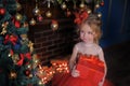 Girl at the Christmas tree in a red elegant dress with a box with gifts in her hands Royalty Free Stock Photo