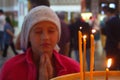 A girl in church is praying. Candles in the temple. Prayer to God