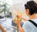 A girl in the church sets a burning candle in a candlestick.