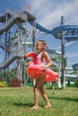 Girl with circle-flamingo stands at high structures of slides of water park Royalty Free Stock Photo
