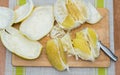 Girl cleans a pomelo on a wooden board Royalty Free Stock Photo