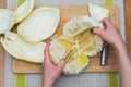 Girl cleans a pomelo on a wooden board Royalty Free Stock Photo