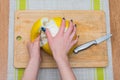 Girl cleans a pomelo on a wooden board Royalty Free Stock Photo