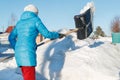 Girl cleans snow shovel on the site near his house. sunlight Royalty Free Stock Photo