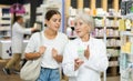 Girl client consults with mature pharmacist which medicinal ointment to buy