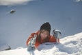 Girl climber climbs a snow cornice using ice axes through snow blown away by the strong wind. Royalty Free Stock Photo