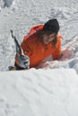 Girl climber climbs a snow cornice using ice axes through snow blown away by the strong wind. Royalty Free Stock Photo