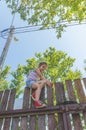 Girl climbs the fence on a summer day Royalty Free Stock Photo