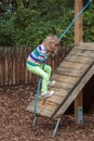 girl climbs a rope on a wooden slope on a modern Playground outdoors