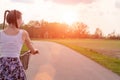 Girl close up with bike at the summer sunset on the road in the city park. Cycling down the street to work at summer sunset. Royalty Free Stock Photo