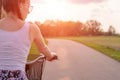 Girl close up with bike at the summer sunset on the road in the city park. Cycling down the street to work at summer sunset. Royalty Free Stock Photo