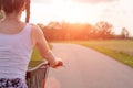 Girl close up with bike at the summer sunset on the road in the city park. Cycling down the street to work at summer sunset. Royalty Free Stock Photo