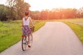 Girl close up with bike at the summer sunset on the road in the city park. Cycling down the street to work at summer sunset. Royalty Free Stock Photo
