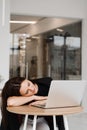 Girl with closed eyes have a break at work and sleeping and relaxing at laptop on workplace due to overtime work. Royalty Free Stock Photo