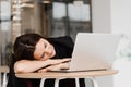 Girl with closed eyes have a break at work and sleeping and relaxing at laptop on workplace due to overtime work. Royalty Free Stock Photo