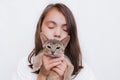 A girl with closed eyes with her pet kitten on her hands posing for the camera Royalty Free Stock Photo