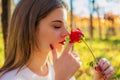 Girl with closed eyes sniffing a red rose