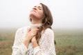 Girl closed her eyes, praying in a field during beautiful fog. Hands folded in prayer concept for faith Royalty Free Stock Photo