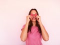 Girl closing eyes with two carton paper small little heart figures at pink background