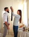 Girl clothe her boyfriend tie in room lit by the sun