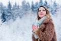 Girl in coat with cup of drink in a snow forest