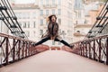 A girl in a coat with her hair down jumps emotionally on a bridge in the old city of Lyon. France. Girl in a coat in France