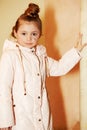 Girl in coat stands, leaning one hand on pillar Royalty Free Stock Photo