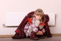 Girl in coat warm near radiator. Crisis.